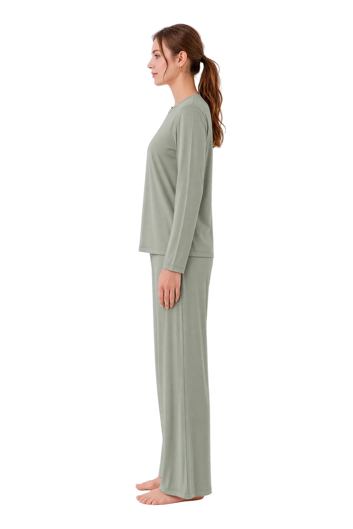 A woman stands in profile wearing a matching two-piece lounge set consisting of a long-sleeve top and wide-leg pants in a muted sage green color, set against a plain white studio background.