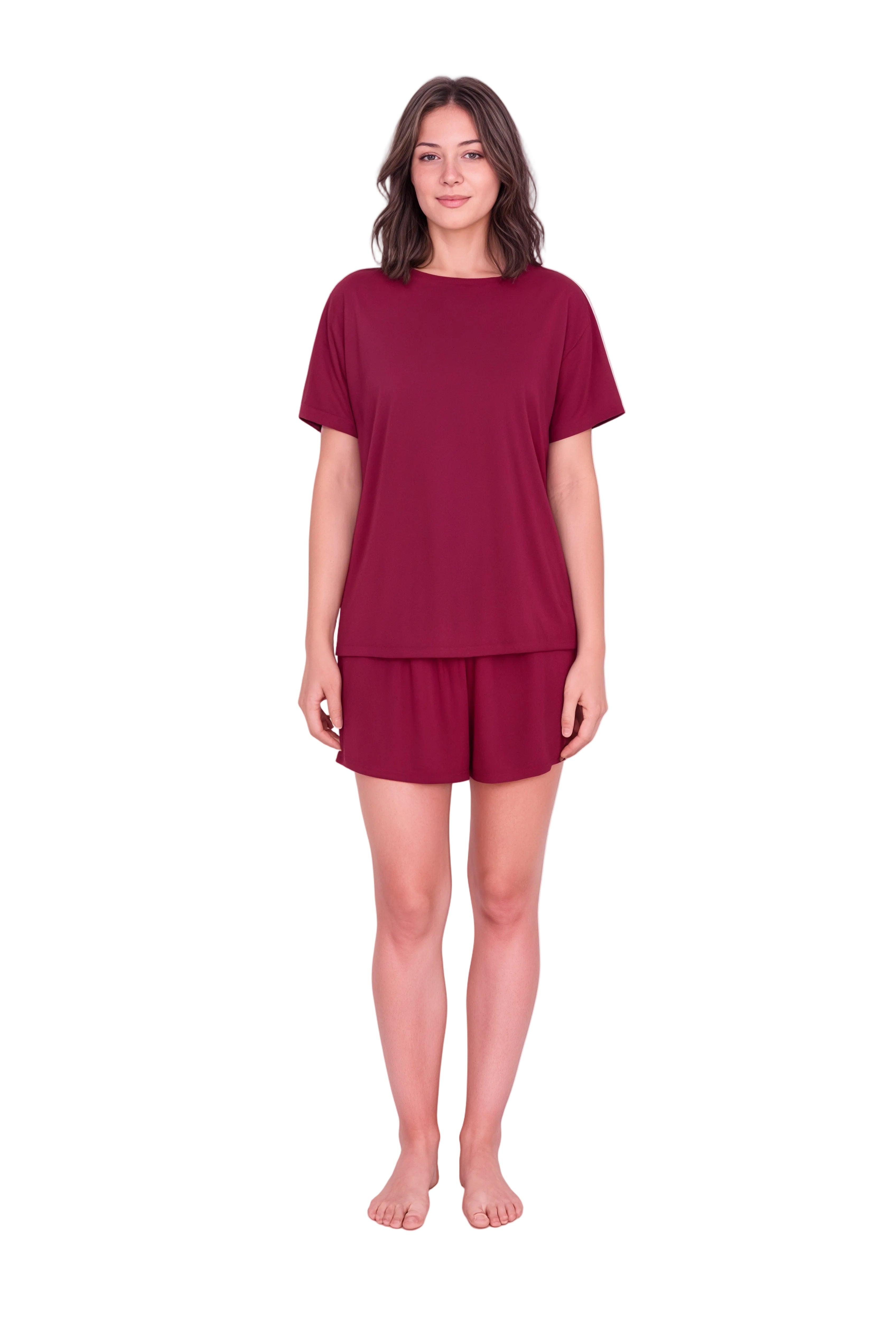 A woman modeling a matching two-piece lounge set consisting of a short-sleeve crewneck top and matching shorts in a deep burgundy color, standing against a plain light pink studio background.