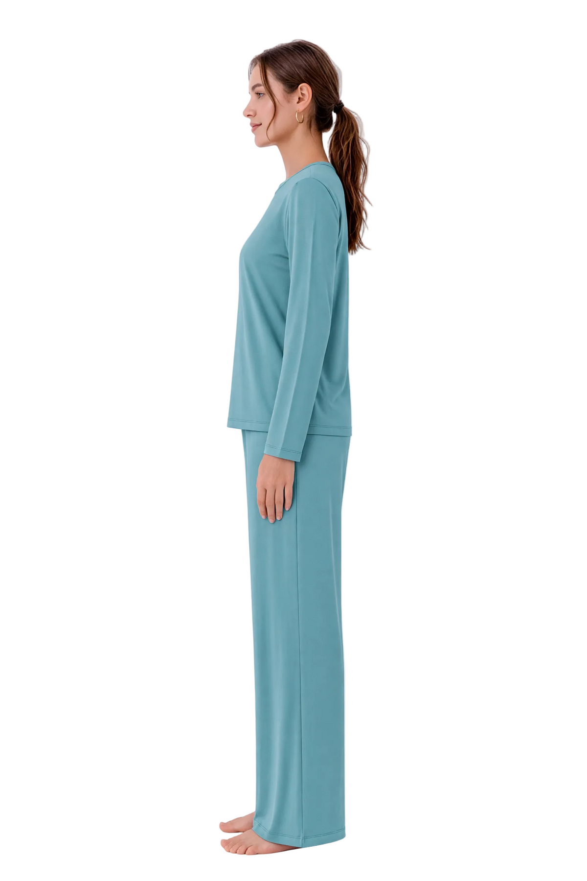 A woman stands in profile wearing a matching two-piece loungewear set in a soft teal blue color, consisting of a long-sleeve top and wide-leg pants, against a plain white background.